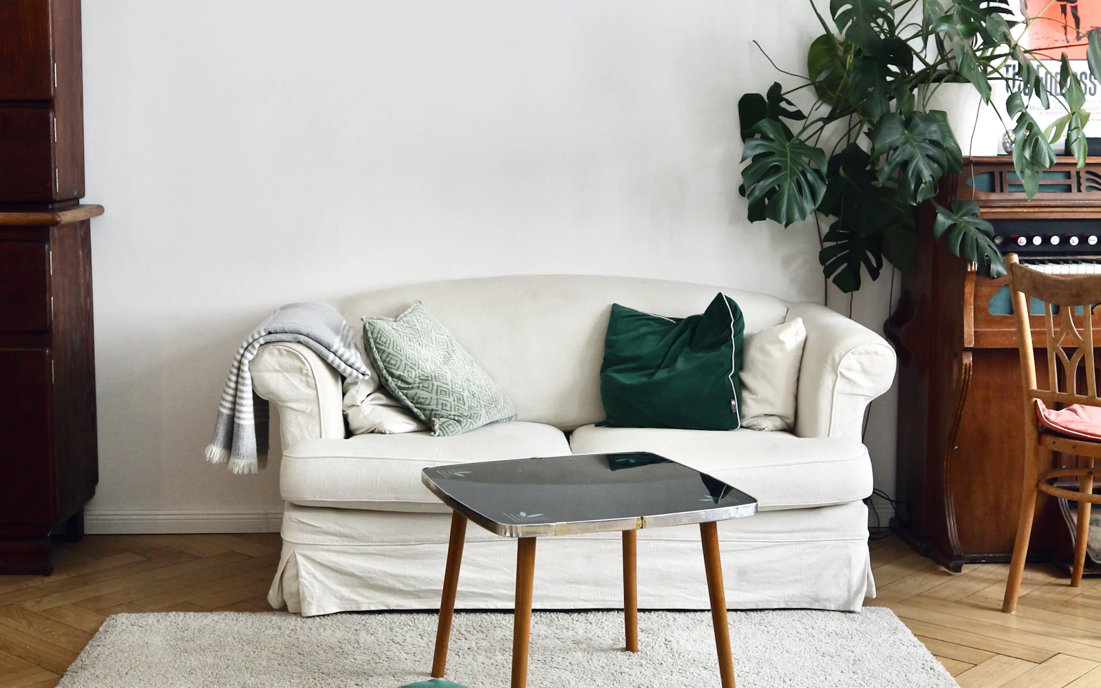 White sofa with a green cushion next to a large plant