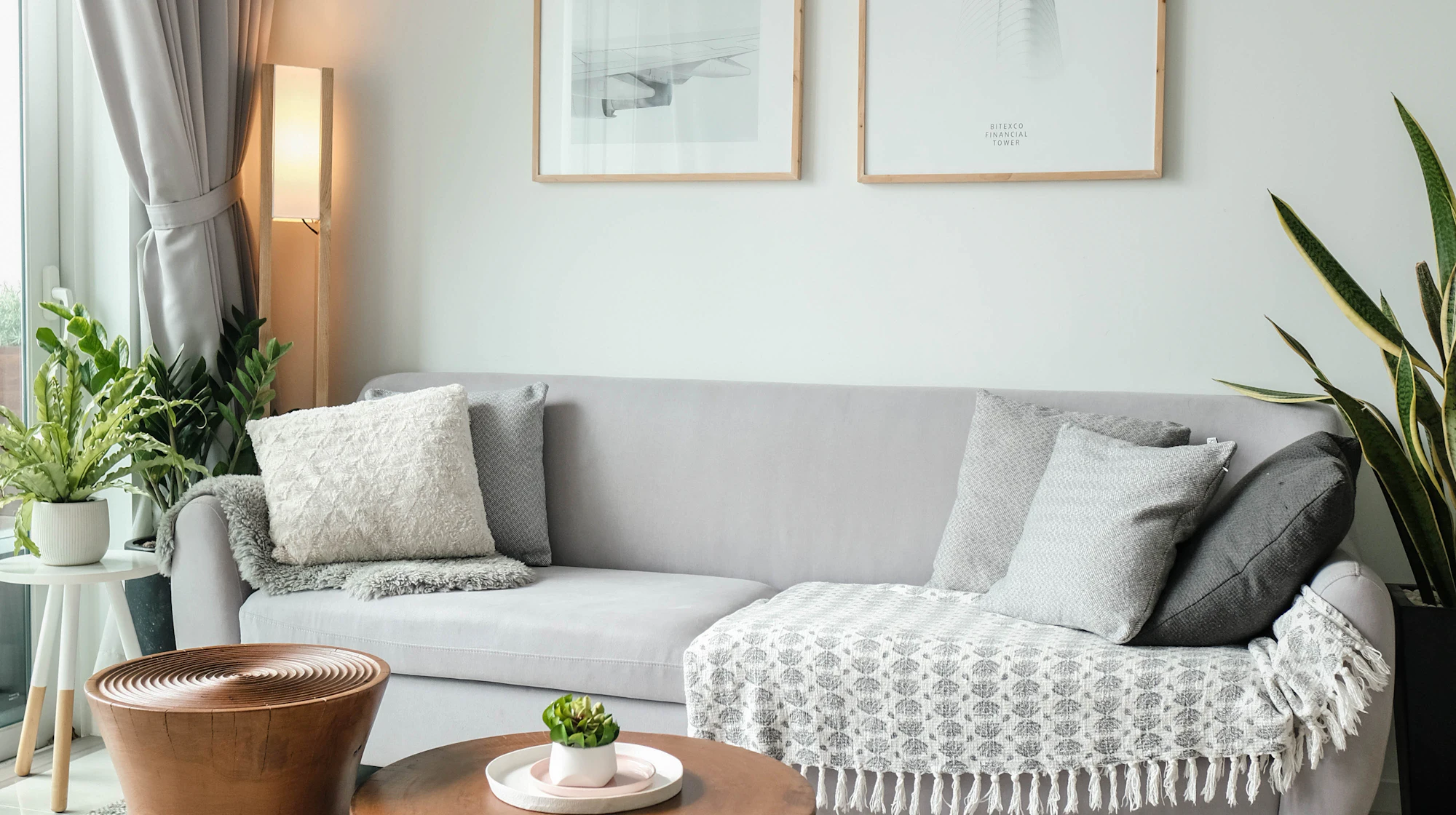 Bright, minimal living room with a soft, pale sofa beside a large window